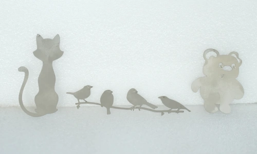 Laser-cut metal sample featuring cat, bird, and bear silhouettes
