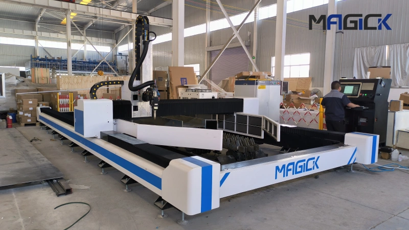 Angled factory view of the MK-HX H beam cutting machine with steel profiles on the bed and an operator at the CNC console